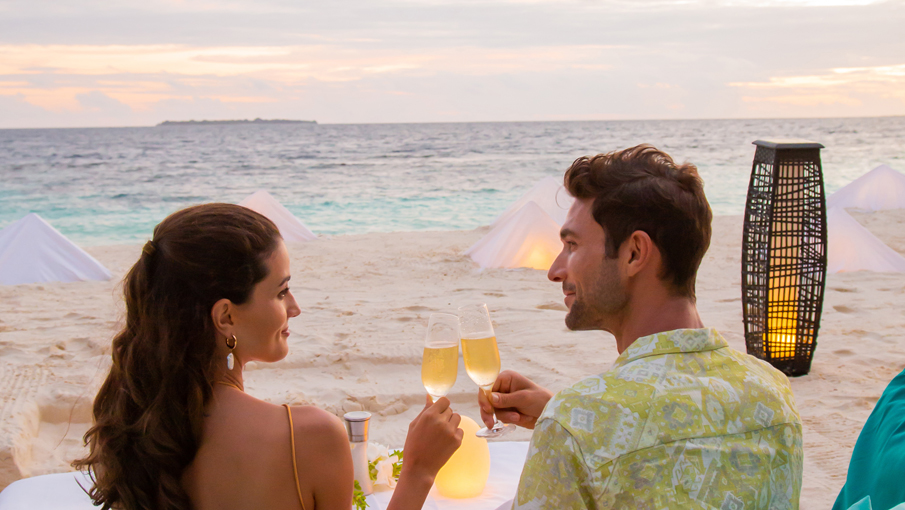 dusit-thani-maldives-experience-beach-couple-sunset-drinks-closeup-905x510